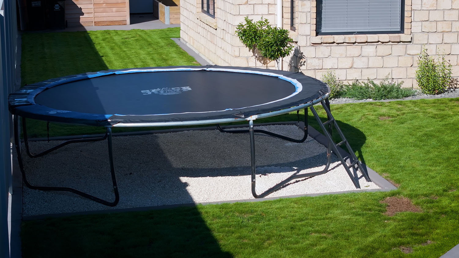 Round trampoline set on a level permeable paved base in a backyard lawn