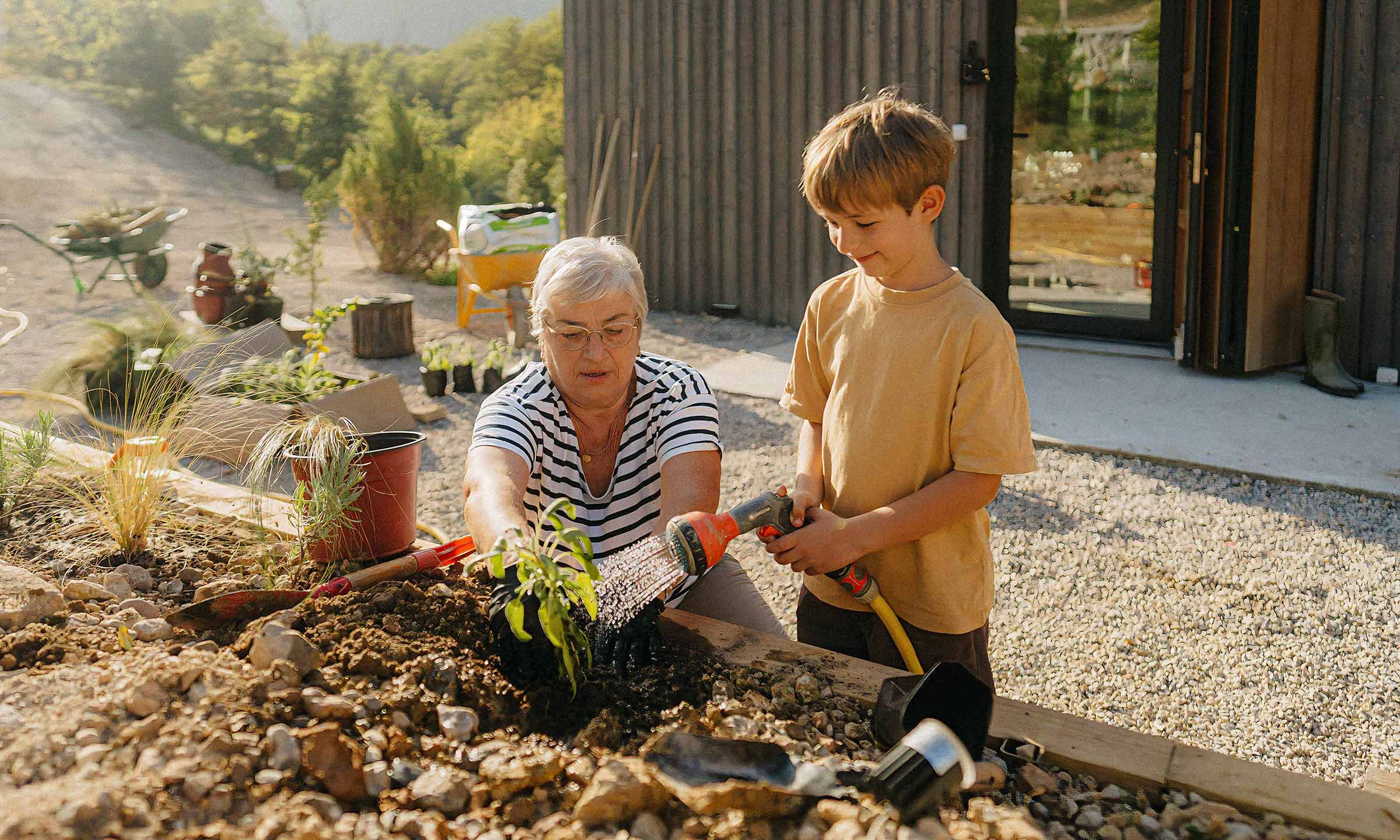 Grandmother and grandson planting in a garden bed