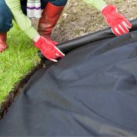 Gardener laying a weed barrier fabric